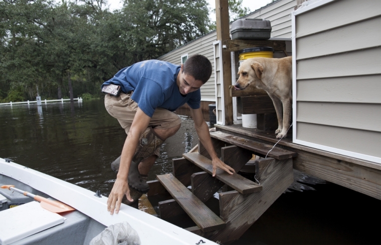 Michael Carroll checks on his dog Bailey on flooded property in Conway, South Carolina, October 6, 2015. The Carroll family has been living with several feet of water on their land since Saturday. Fourteen people have died amid historic rainfall in South Carolina, the state's governor said on Tuesday, as residents grappled with the damage wrought by flooding on their homes, roads and water supply.