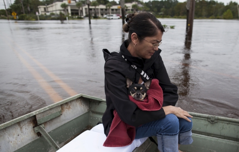 Miki Woodward holds family dog Butch while sitting on a johnboat along Waccamaw Drive in Conway, South Carolina, October 6, 2015.