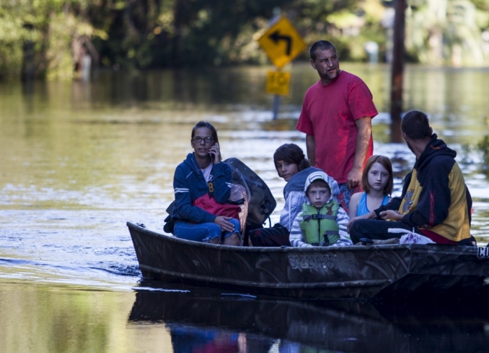 Scott Everett (standing) transports his family on a johnboat along Lee's Landing Circle in Conway, South Carolina October 7, 2015. Rescuers searched early Wednesday for two people missing in floodwaters in South Carolina, while authorities urged residents in hundreds of homes to seek higher ground.