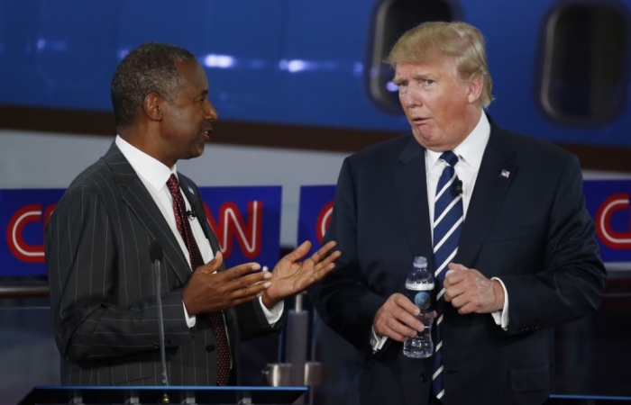 Republican U.S. presidential candidates Dr. Ben Carson (L) and businessman Donald Trump talk during a commercial break at the second official Republican presidential candidates debate, September 16, 2015.