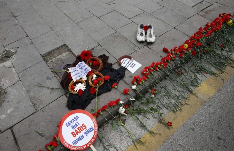 A pair of shoes, belonging to a street vendor who was selling Turkish traditional bagel or simit, is placed at the bombing scene during a commemoration for the victims of Saturday's bomb blasts, in Ankara, Turkey, October 12, 2015. Islamic State is the focus of investigations into a twin suicide bombing that killed at least 97 people in the Turkish capital Ankara and investigators are close to identifying one of the suspects, Prime Minister Ahmet Davutoglu said on Monday. Speaking on Turkish broadcaster NTV in a live interview, Davutoglu said Saturday's attack was an attempt to influence the outcome of a parliamentary election on Nov. 1 and that necessary steps would be taken if security failures were found to have contributed to the bombing. The sign on the left reads, 'Peace now immediately, despite the war'.