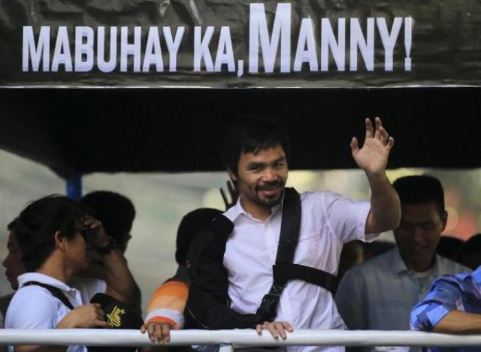 Boxer Manny Pacquiao waves to crowds during a motorcade in Manila, Philippines after arriving from Las Vegas, Nevada, May 13, 2015.