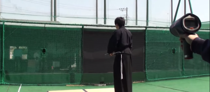 A samurai waits for the pitch in the batting cage.