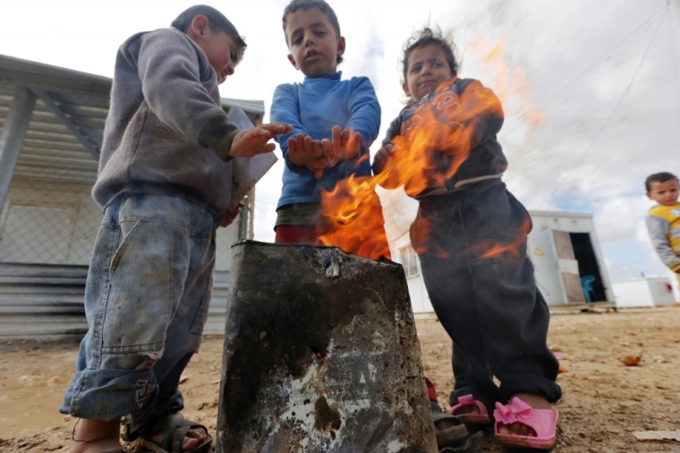 Syrian refugees children warm themselves after a heavy snowstorm at Al Zaatari refugee camp in the Jordanian city of Mafraq, near the border with Syria, February 21, 2015.