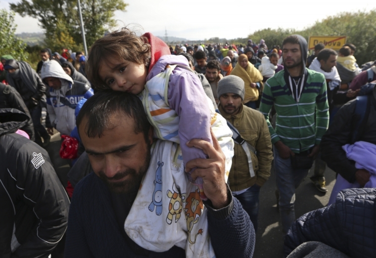 A migrant carries a child as they continue their journey in Dobova, Slovenia, October 20, 2015. Migrants continue to stream north through the Balkans from Greece but Hungary sealed its border with Croatia on Friday and Slovenia imposed daily limits on migrants entering from Croatia, leaving thousands stuck on cold, rain-sodden frontiers.