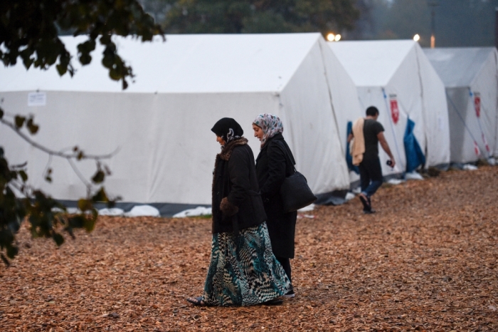 Migrants walk in front of tents in a refugee camp in Celle, Lower-Saxony, October 15, 2015. With the approach of winter, authorities are scrambling to find warm places to stay for the thousands of refugees streaming into Germany every day. In desperation, they have turned to sports halls, youth hostels and empty office buildings. But as these options dry up, tent cities have become the fall-back plan: despite falling temperatures, a survey by German newspaper Die Welt showed at least 42,000 refugees were still living in tents.