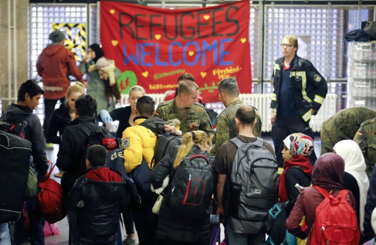 Volunteers and German Bundeswehr, armed forces soldiers, distrubute food to migrants before they are transported by bus to a refugee camp in the capital after arriving by train from Salzburg, Austria, at Schoenefeld railway station in Berlin, Germany, October 5, 2015.