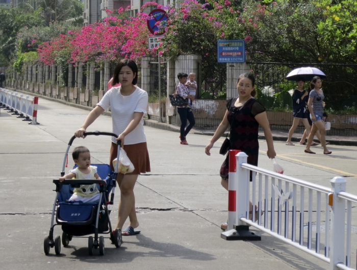 Wu Tingting (L) pushes a stroller carrying her 1-year-old daughter, as she shops for morning groceries in a residential suburb of Zhuhai, close to the Pearl River, in southern China, October 30, 2015. China has unwound its one-child policy, for decades a symbol of invasive and coercive government planning, but the shift has been met with a disinterested shrug from many younger couples.