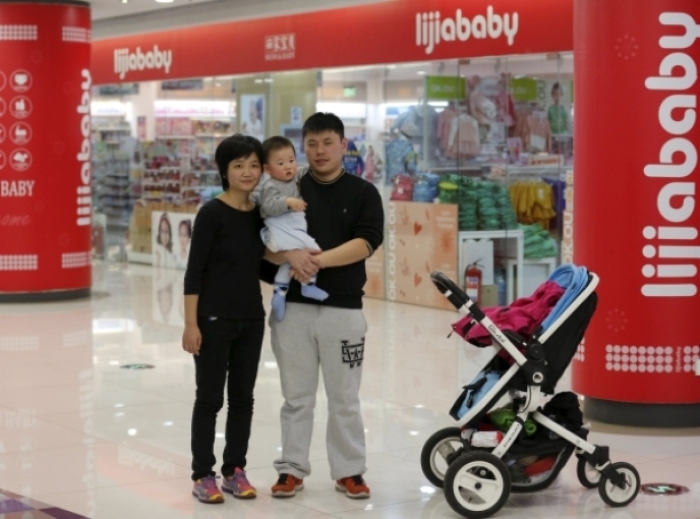 Wife, husband and baby in front a baby shop in Beijing October 30, 2015.