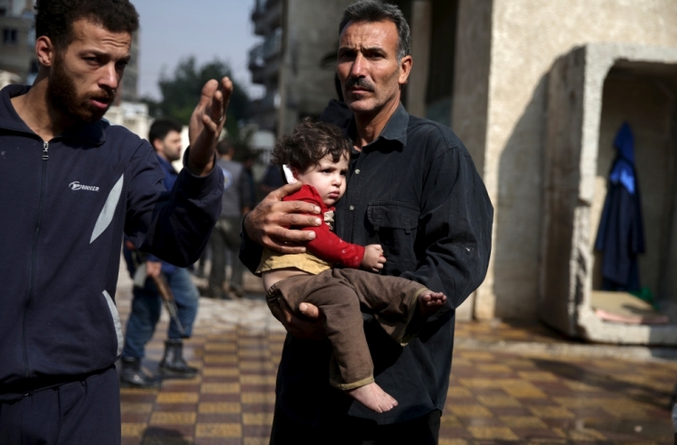 A man carries an injured child as another man gestures at a site hit by missiles fired by Syrian government forces on a busy marketplace in the Douma neighborhood of Damascus, Syria, October 30, 2015. At least 40 people were killed and about 100 wounded after Syrian government forces fired missiles into the market place in a town near Damascus, a conflict monitor and a local rescue group said on Friday.