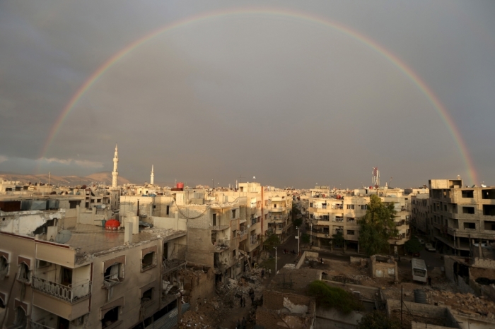 A rainbow is seen as residents inspect a site damage from what activists said was an airstrike by forces loyal to Syria's President Bashar al-Assad on the main field hospital in the town of Douma, eastern Ghouta in Damascus, October 29, 2015.