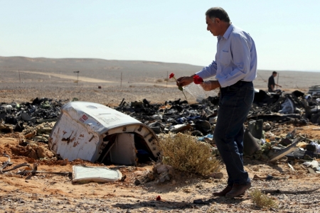 An Egyptian man puts flowers near debris at the crash site of a Russian airliner in al-Hasanah area at El Arish city, north Egypt, November 1, 2015. In a desolate area of stony ground, little remains from the Russian airliner that crashed in Egypt's Sinai Peninsula except its blackened wreckage and a heap of colorful suitcases. Rescue teams scoured the area where the Airbus A321 came down on Saturday, collecting into a pile the dead holidaymakers' belongings that were spread around the main part of the wreckage.