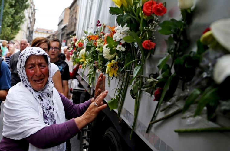 A woman cries beside a truck carrying 136 coffins of newly identified victims of the 1995 Srebrenica massacre, in front of the presidential building in Sarajevo, July 9, 2015. The bodies of the 136 recently identified victims of Srebrenica massacre will be transported to the memorial centre in Potocari where they will be buried on July 11, the anniversary of the massacre when Bosnian Serb forces slaughtered 8,000 Muslim men and boys and buried them in mass graves in Europe's worst massacre since World War Two.
