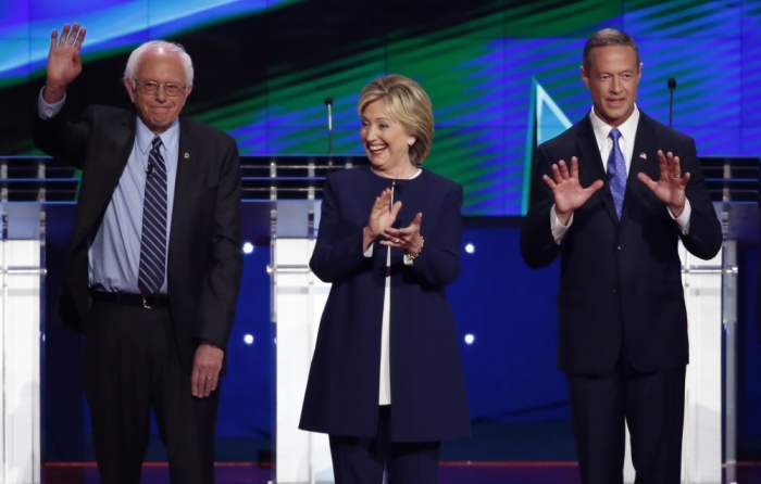 Democratic presidential candidates U.S. Senator Bernie Sanders (L), former Secretary of State Hillary Clinton (C) and an unidentified man react to the crowd before the start of the first official Democratic candidates debate of the 2016 presidential campaign in Las Vegas, Nevada, October 13, 2015.
