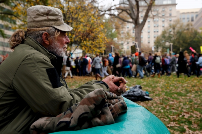 Steve Stoppelbein, a homeless man who says he has lived in Franklin Square for about a year, watches as students march out of the park for an 'Our Generation, Our Choice' protest in downtown Washington November 9, 2015. The Monday march to highlight race, climate, and immigration issues was timed to mark exactly one year until the 2016 U.S. presidential election, according to protesters.