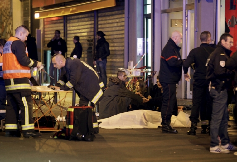 A general view of the scene that shows rescue services personnel working near the covered bodies outside a restaurant following a shooting incident in Paris, France, November 13, 2015.