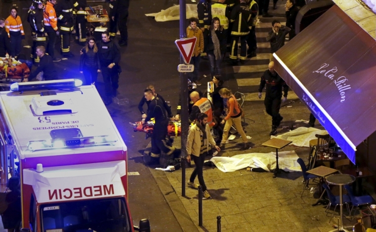 French fire brigade members aid an injured individual near the Bataclan concert hall following fatal shootings in Paris, France, November 13, 2015. At least 30 people were killed in attacks in Paris and a hostage situation was under way at the concert hall in the French capital, French media reported on Friday.