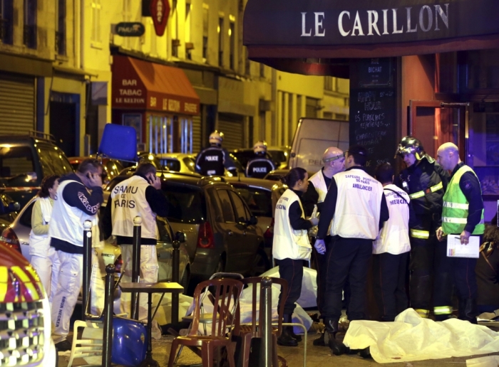 A general view of the scene shows rescue service personnel working near the covered bodies outside a restaurant following a shooting incident in Paris, France, November 13, 2015.