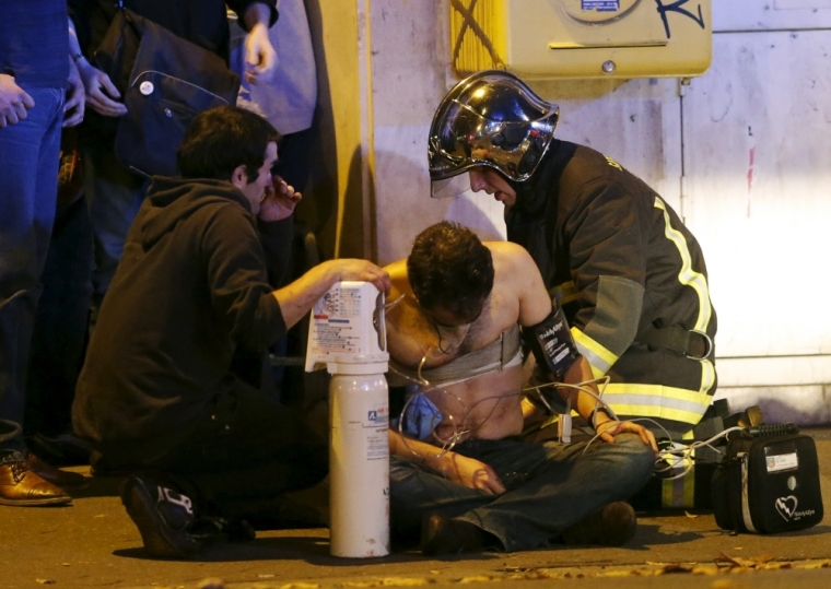 French fire brigade members aid an injured individual near the Bataclan concert hall following fatal shootings in Paris, France, November 13, 2015.