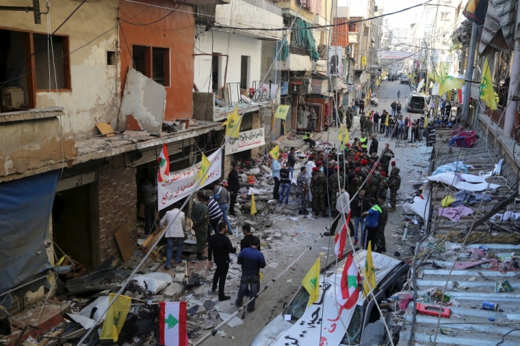 Lebanese army soldiers and security forces gather as Lebanese and Hezbollah flags are erected at the site of the two explosions that occured on Thursday in the southern suburbs of the Lebanese capital Beirut, November 13, 2015.