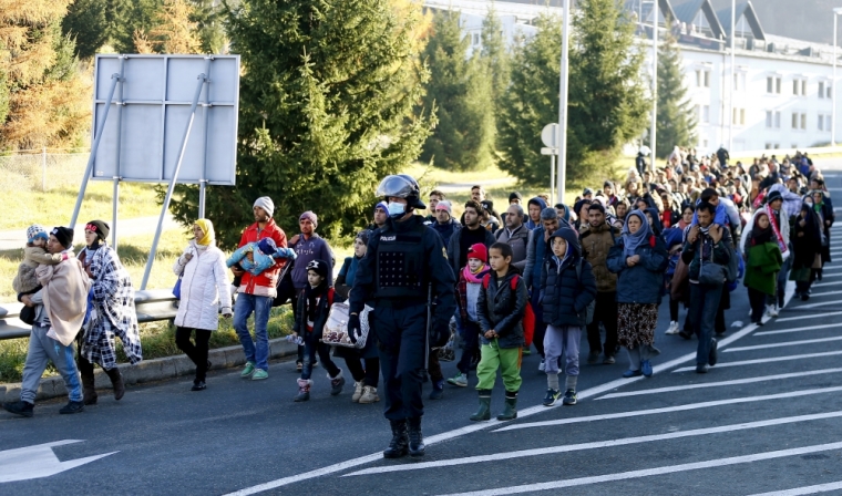 Slovenian police officers guide migrants towards the Austrian border town of Spielfeld in the village of Sentilj, Slovenia, November 18, 2015.