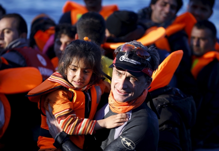 A German volunteer carries a Syrian refugee girl off an overcrowded raft after landing at a rocky beach in the Greek island of Lesbos, November 19, 2015. Balkan countries have begun filtering the flow of migrants to Europe, granting passage to those fleeing conflict in the Middle East and Afghanistan but turning back others from Africa and Asia, the United Nations and Reuters witnesses said on Thursday.