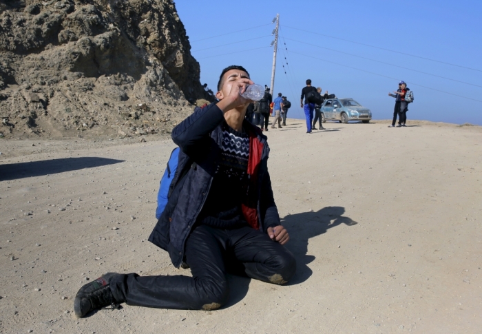 An exhausted Syrian refugee drinks water after arriving by a raft on the Greek island of Lesbos, November 19, 2015. Balkan countries have begun filtering the flow of migrants to Europe, granting passage to those fleeing conflict in the Middle East and Afghanistan but turning back others from Africa and Asia, the United Nations and Reuters witnesses said on Thursday.
