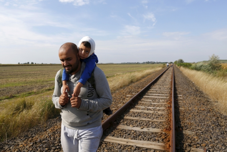 Syrian immigrants walk on a railway track after they crossed the Hungarian-Serbian border near Roszke, Hungary, August 25, 2015.