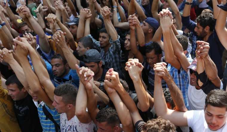 Syrian refugees raise their arms in front of the railways station in Budapest, Hungary, September 2, 2015.