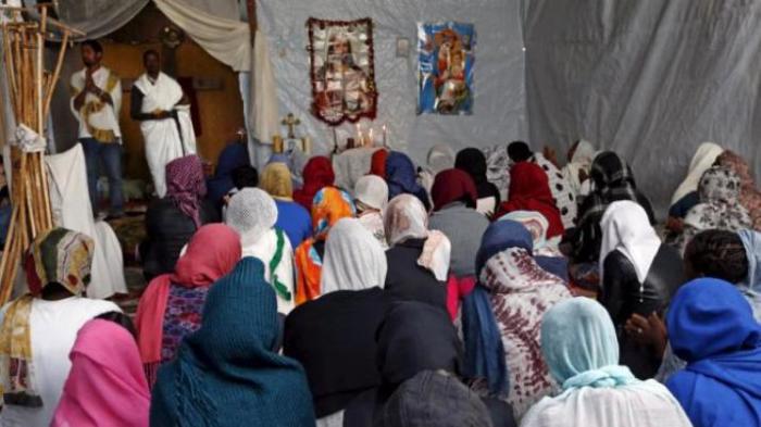 Christian migrants from Eritrea and Ethiopia pray during the Sunday mass at the makeshift church in 'The New Jungle' near Calais, France, August 2, 2015.