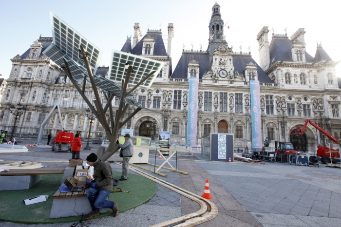 Employees work under solar panels during the installation of the exhibition 'Paris de L'Avenir', a showcase for tangible climate solutions in the context of the COP21 World Climate Summit, in front of Paris city hall, France, November 26, 2015. The conference of the 2015 United Nations Framework Convention on Climate Change will start on November 30 in Le Bourget near the French capital.
