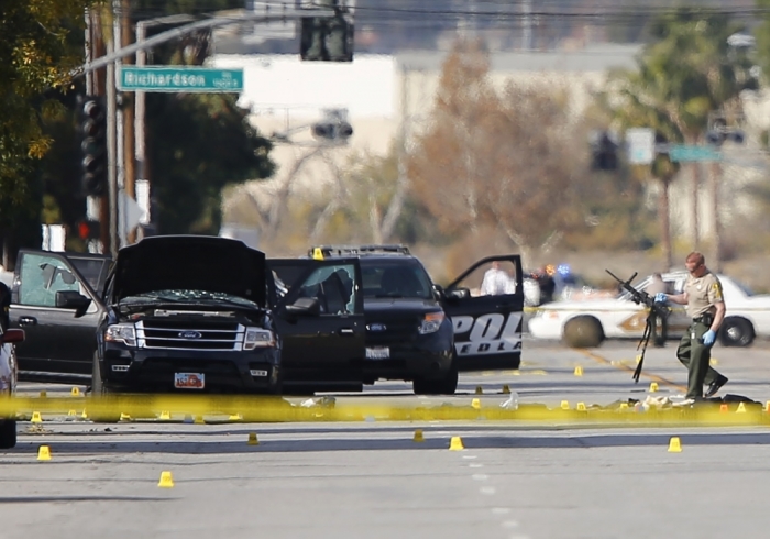 A police officer picks up a weapon from the scene of the investigation around the area of the SUV vehicle where two suspects were shot by police following a mass shooting in San Bernardino, California, December 3, 2015. Authorities on Thursday were working to determine why Syed Rizwan Farook 28, and Tashfeen Malik, 27, who had a 6-moth old daughter together, opened fire at a holiday party of his co-workers in Southern California, killing 14 people and wounding 17 in an attack that appeared to have been planned.