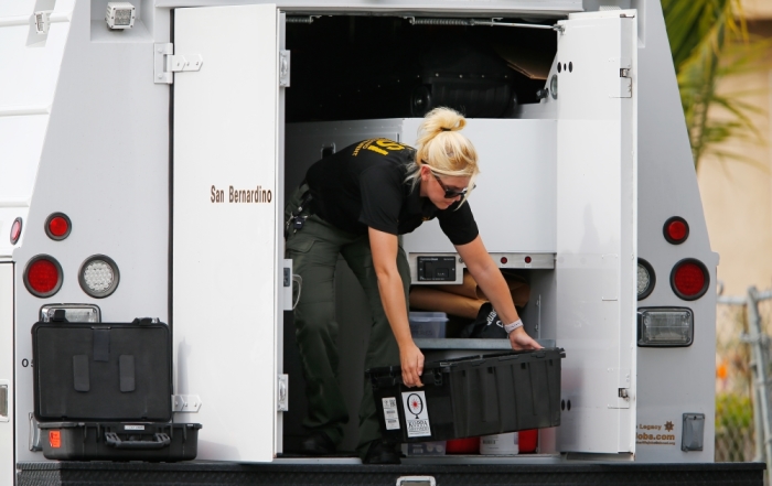 A Sheriff's Office Crime Scene Iinvestigator unloads equipment at the scene of the investigation around an SUV where two suspects were shot by police following a mass shooting in San Bernardino, California, December 3, 2015. Authorities on Thursday were working to determine why Syed Rizwan Farook 28, and Tashfeen Malik, 27, opened fire at a holiday party of his co-workers in Southern California, killing 14 people and wounding 17 in an attack that appeared to have been planned.