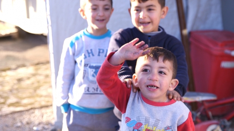 Refugees seeking to flee war-torn Iraq smile for cameras.