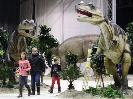 Children walk by life-sized Ceratosaurus dinosaur models in Vienna February 7, 2014. The travelling exhibition "World of Dinosaurs" shows some 50 life-sized dinosaur models and runs in Vienna until February 23.