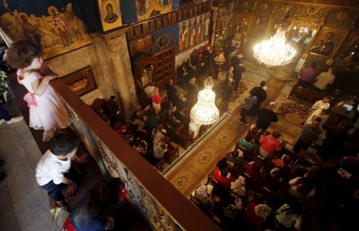 Credit : Palestinian children watch worshippers as they attend Orthodox Christian Palm Sunday mass at the Saint Porfirios church in Gaza City April 5, 2015.