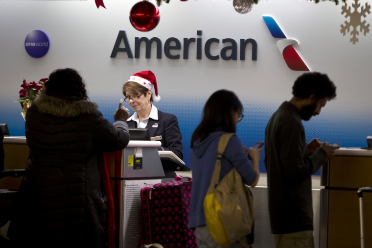 An agent for American Airlines checks in passengers while wearing a Santa hat on the day before Christmas at LaGuardia Airport in New York, December 24, 2014.