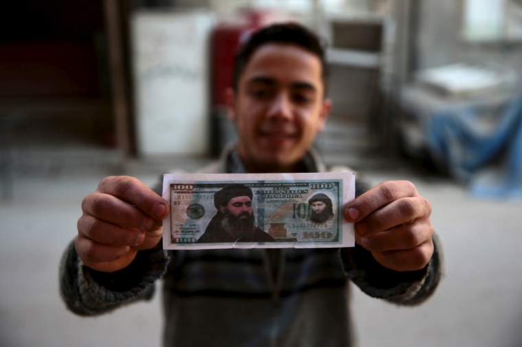 A boy poses while showing one of the fake U.S. 100 dollar banknotes depicting Islamic State's leader Abu Bakr al-Baghdadi (L) and al-Nusra Front's leader Abu Mohammed al-Joulani (R), that were dropped by Syrian army jets in the Douma neighborhood of Damascus, Syria, December 27, 2015.