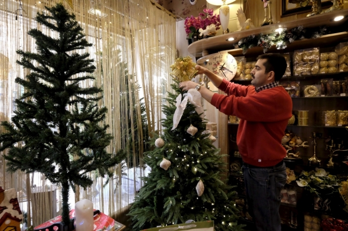 A shopkeeper sets up a Christmas tree at a shop in central Tehran, December 23, 2015.