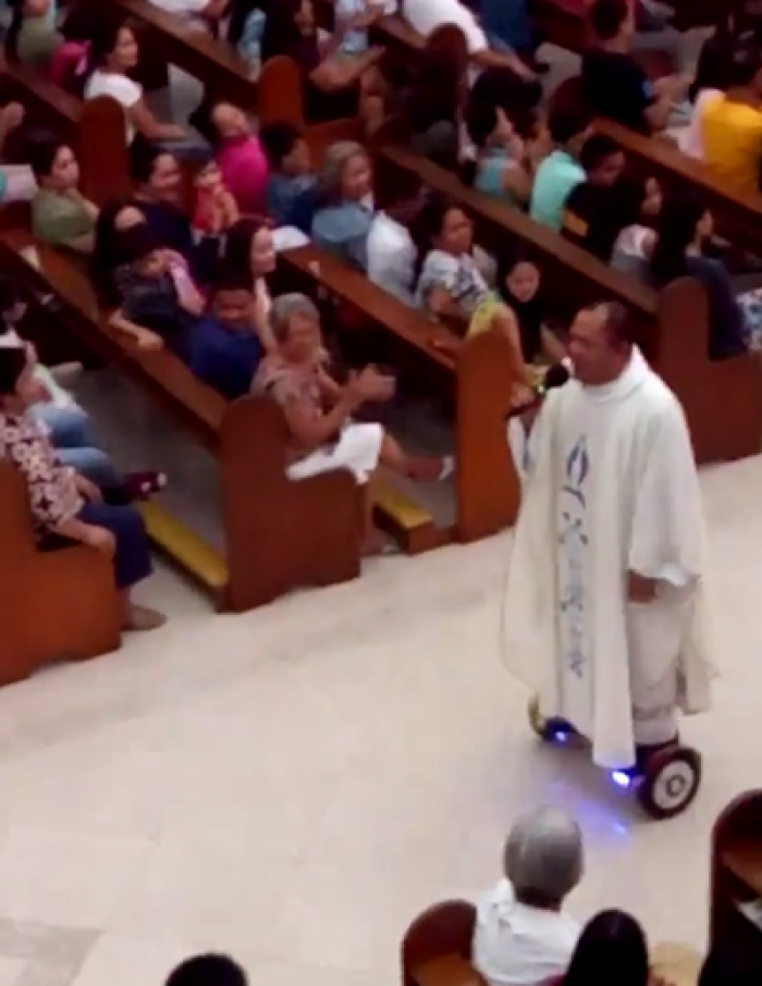 A Catholic priest sings during mass while riding a hoverboard.