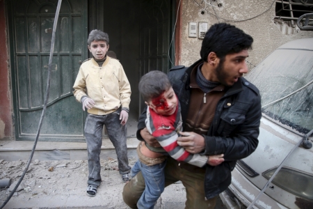 A man carries an injured child in a site damaged from what activists said was shelling by forces loyal to Syria's President Bashar al-Assad in the town of Douma, eastern Ghouta in Damascus, Syria, December 30, 2015.