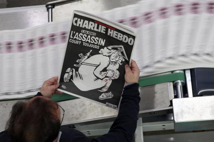 An employee of a printing house holds a copy of the latest edition of French weekly newspaper Charlie Hebdo with the title 'One year on, The assassin still on the run' near Paris, France, January 4, 2016.