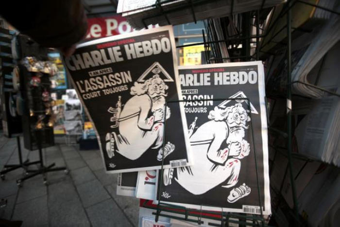 A man takes a copy of the latest edition of French weekly newspaper Charlie Hebdo with the title 'One year on, The assassin still on the run' displayed at a kiosk in Nice, France, January 6, 2016.
