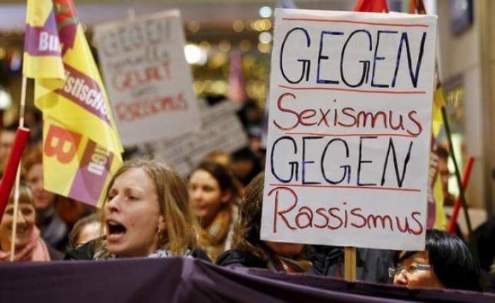 Women shout slogans and hold up a placard that reads 'Against Sexism - Against Racism' as they march through the main railways station of Cologne, Germany, January 5, 2016.