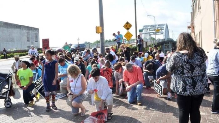 Pro-life advocates kneel in prayer before crossing Edmund Pettus Bridge in Selma, Alabama