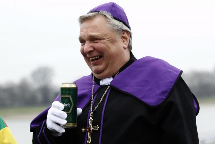 A carnival reveller dressed as a bishop drinks a beer during the traditional Rose Monday carnival parade in the western German city of Duesseldorf March 3, 2014.