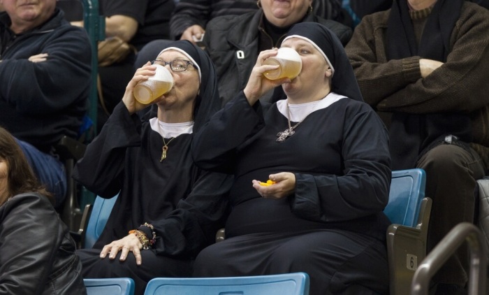 Two women wearing nun outfits drink beer while watching the playoff draw between Quebec and Manitoba at the 2014 Tim Hortons Brier curling championships in Kamloops, British Columbia, March 8, 2014.