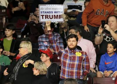A protester (C) stands as republican presidential candidate Donald Trump speaks during a campaign event in Rock Hill, South Carolina January 8, 2016.