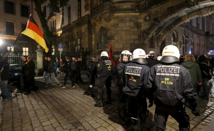 Riot police separate people holding a German flag and on their way to attend an anti-immigration demonstration organised by right wing movement Patriotic Europeans Against the Islamisation of the West (PEGIDA) and opponents of PEGIDA in Dresden, Germany, on October 20, 2015.