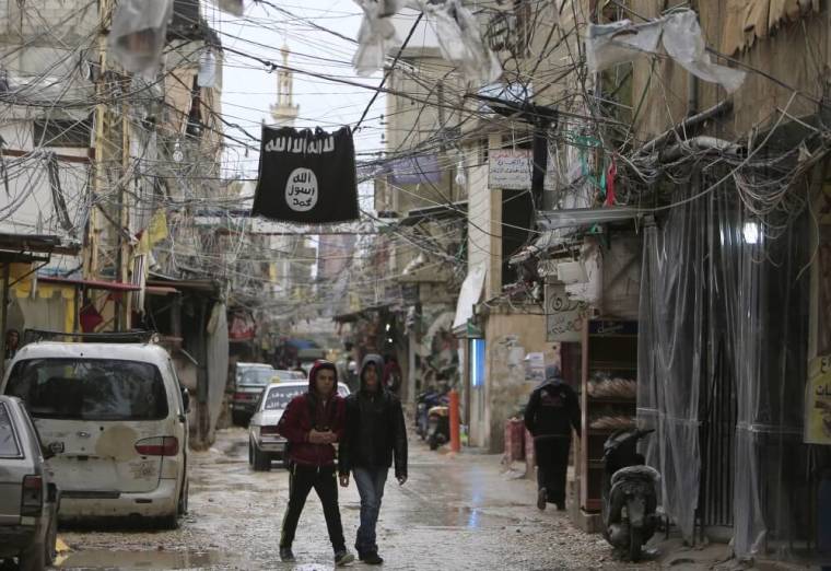 Youth walk under an Islamic State flag in Ain al-Hilweh Palestinian refugee camp, near the port-city of Sidon, southern Lebanon, January 19, 2016.